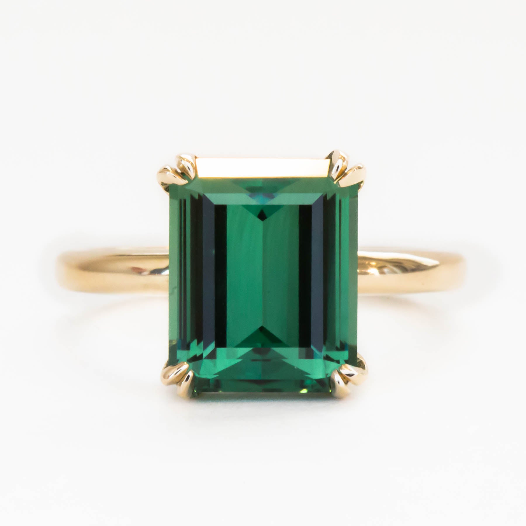 custom double prong yellow gold solitaire with green lab sapphire step cut