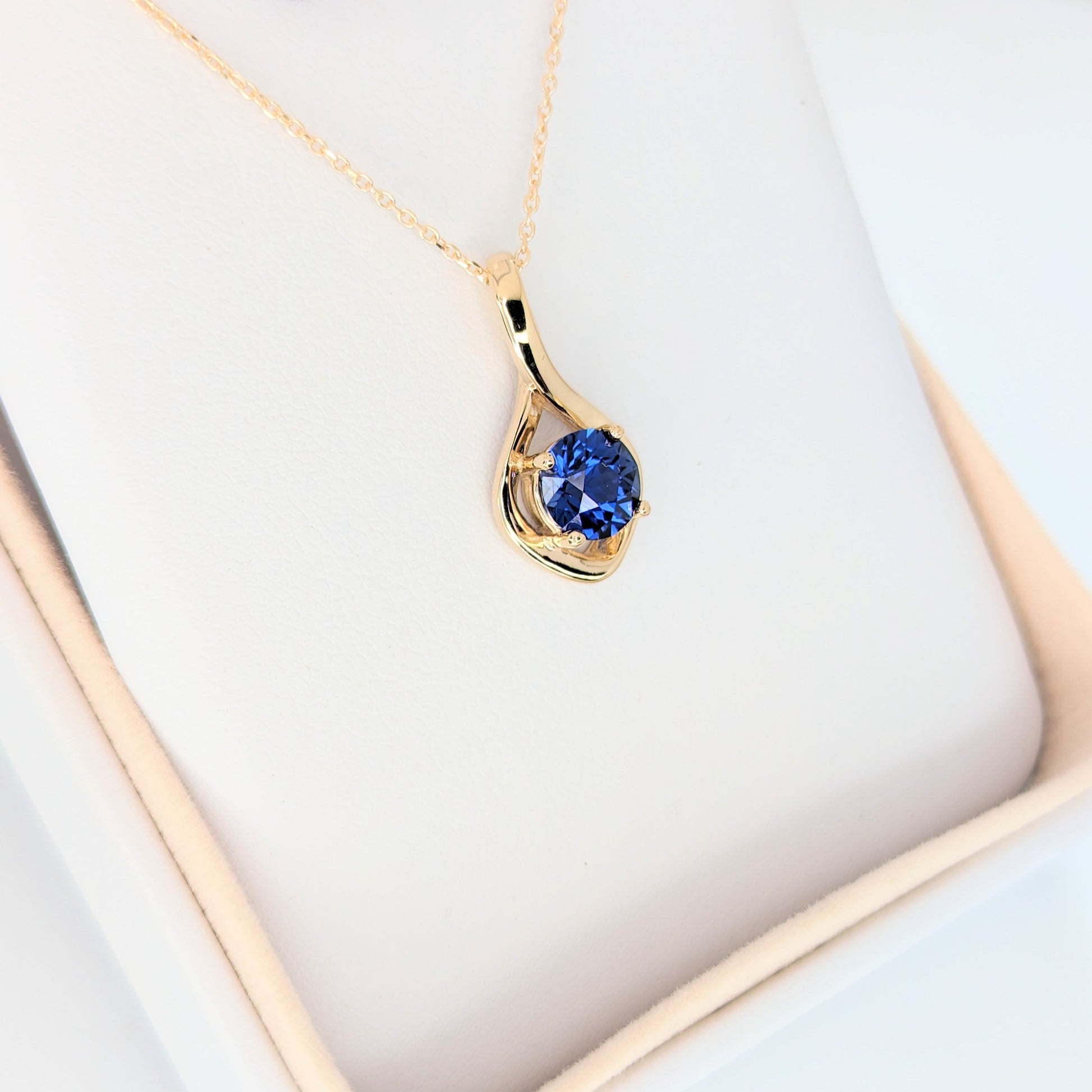 yellow gold infinity necklace with round blue lab sapphire