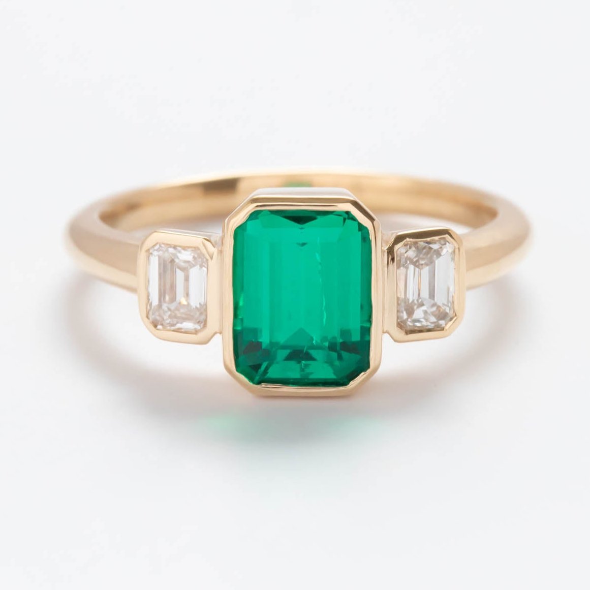 bezel set three stone ring with lab emerald