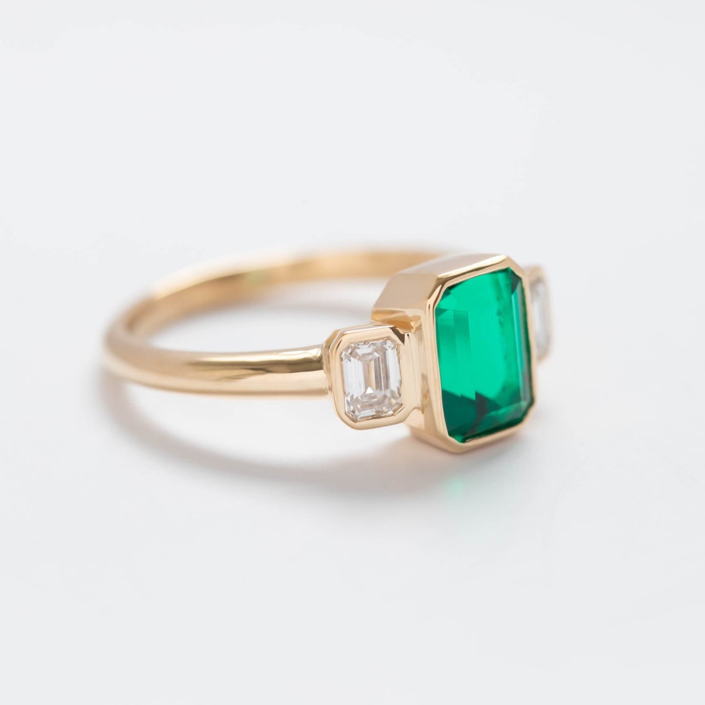 bezel set three stone ring with lab emerald