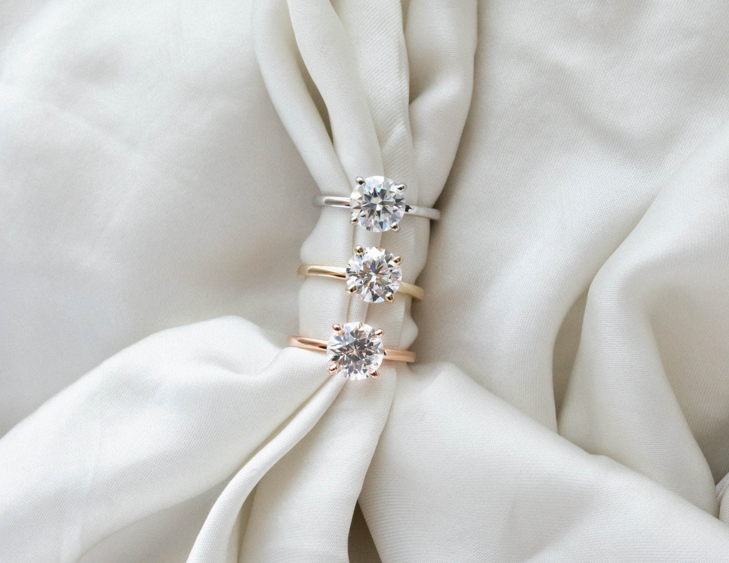 three solitaire engagement rings in white, yellow and rose gold