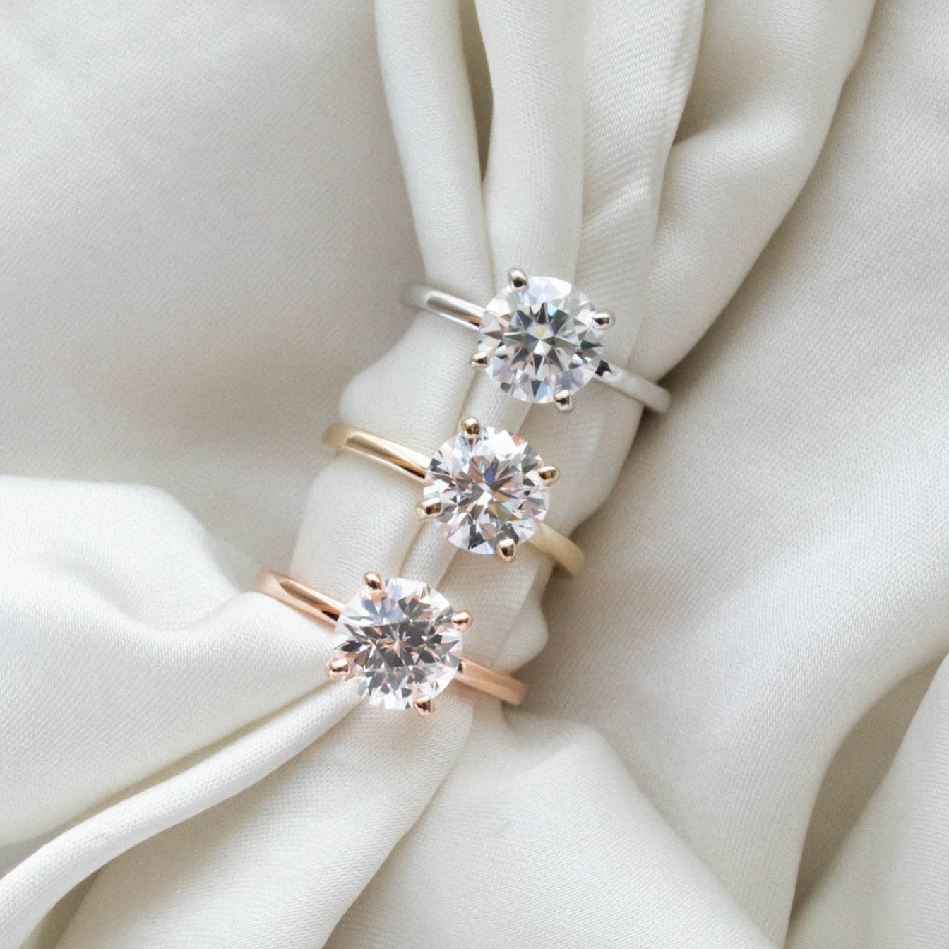 three solitaire engagement rings in white, yellow and rose gold