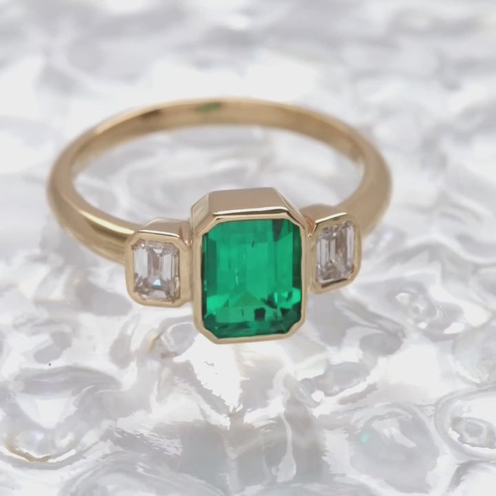 bezel set three stone ring with lab emerald